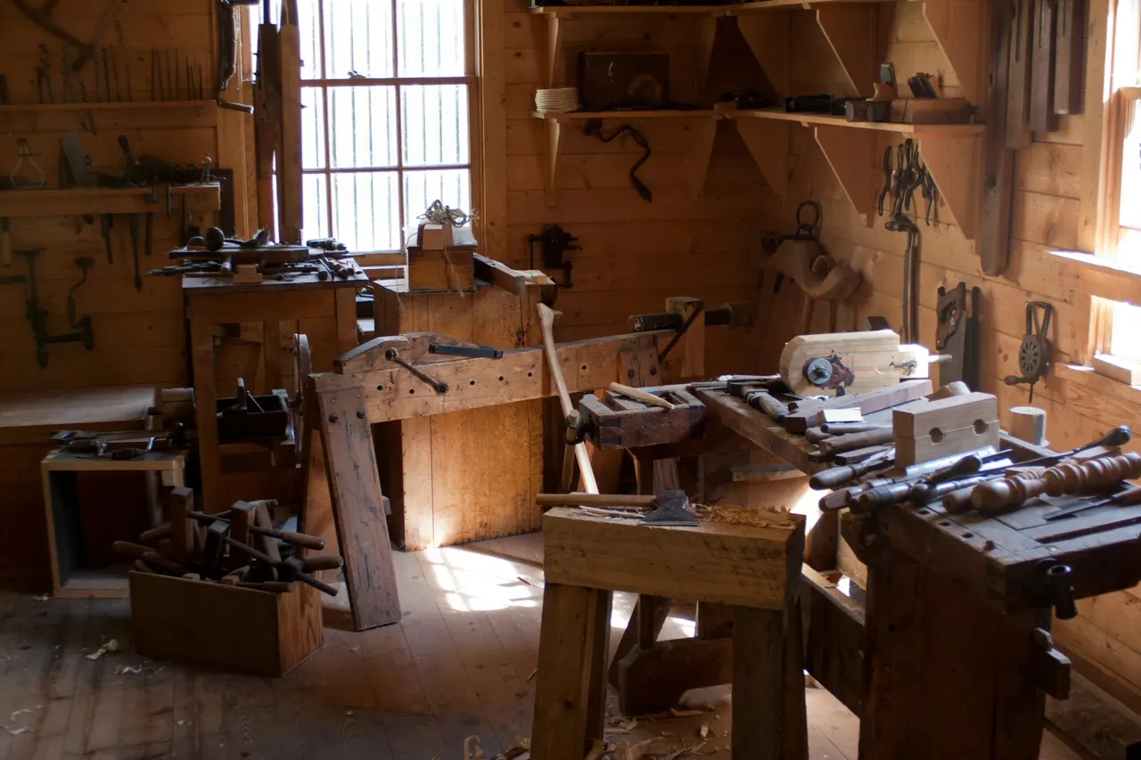 An old wood shop with benches and tools in window light